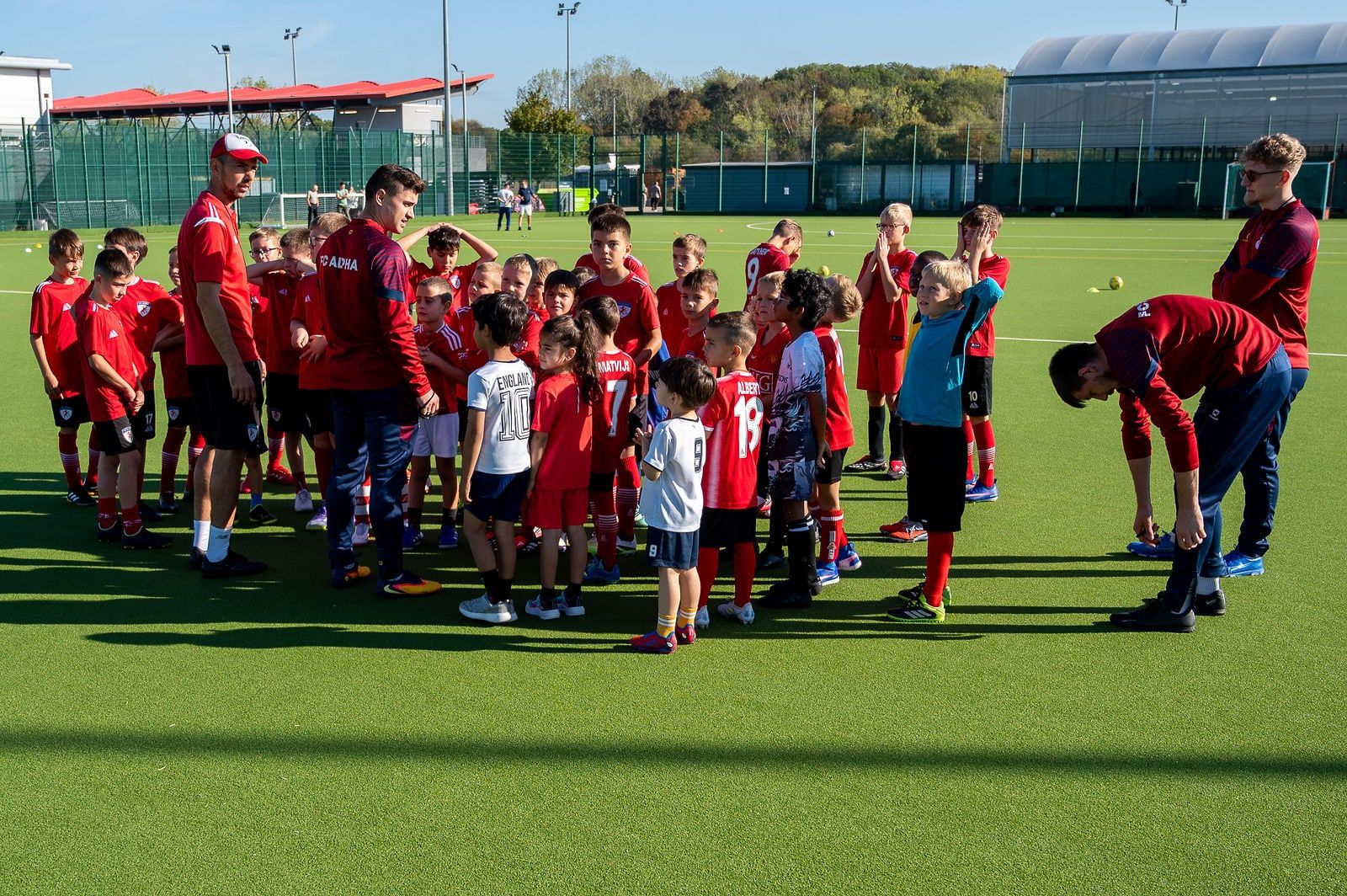 Coaches briefing a large group of academy players on the 3G pitch