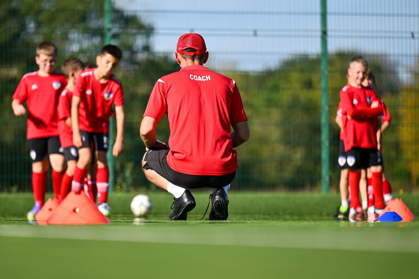 A coach crouching to explain a drill to the group