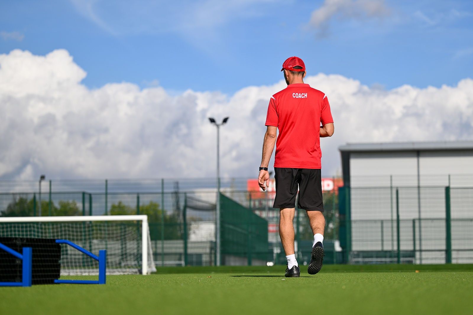 An FC Alpha coach walking across the pitch