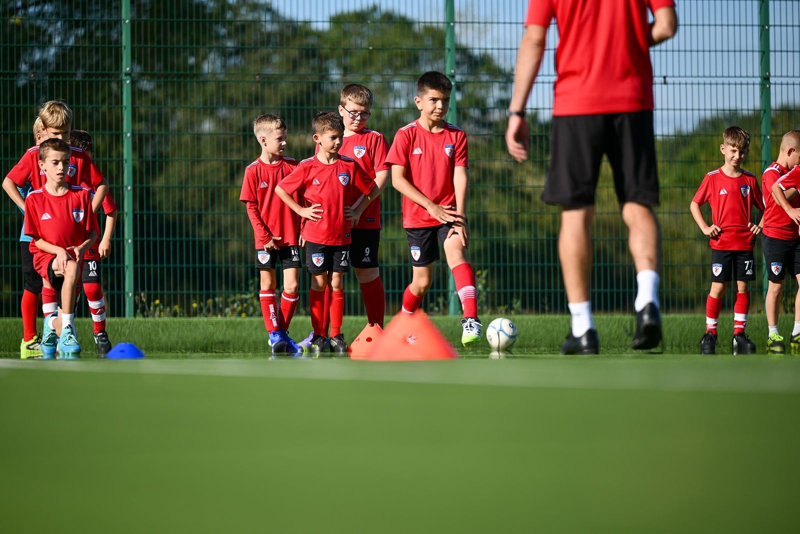 Academy players lined up behind cones listening to the coach